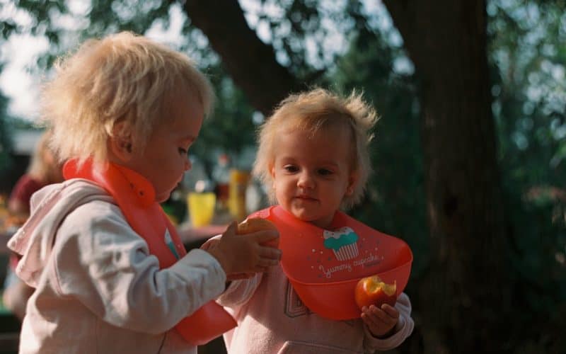 cute babies eating apple and wearing bibs