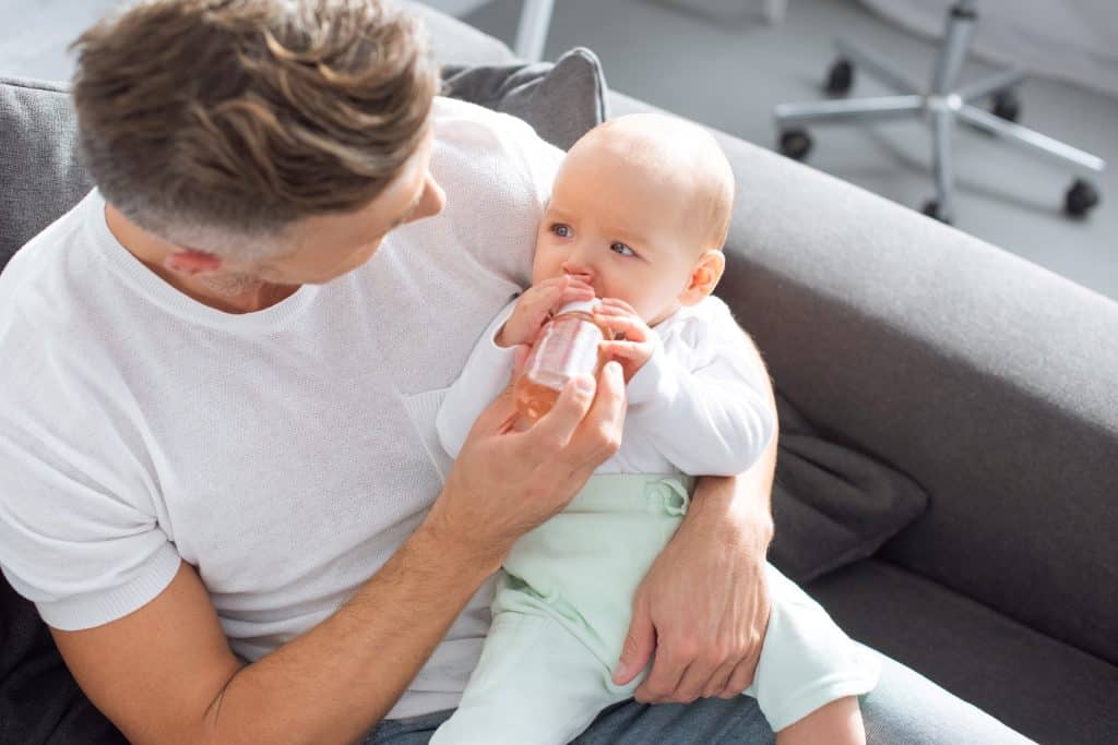 dad feeding milk on baby