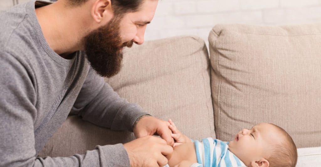 dad smiling while changing baby's diaper