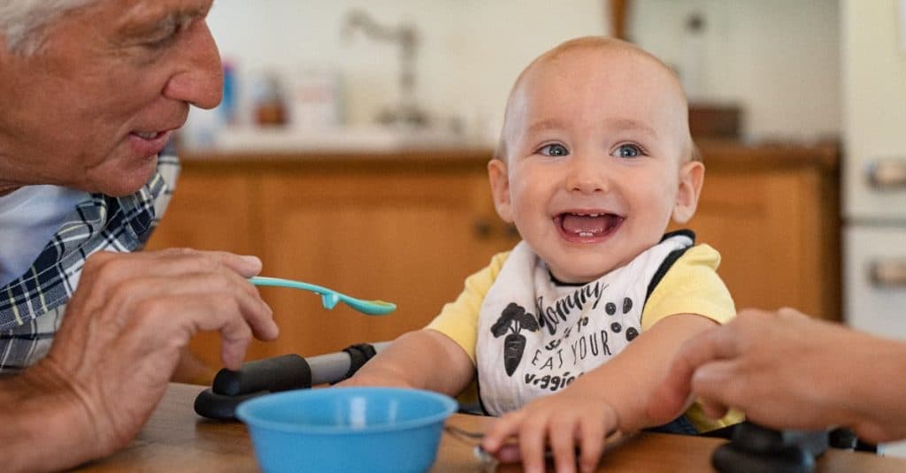 grandpa feeding smiling baby