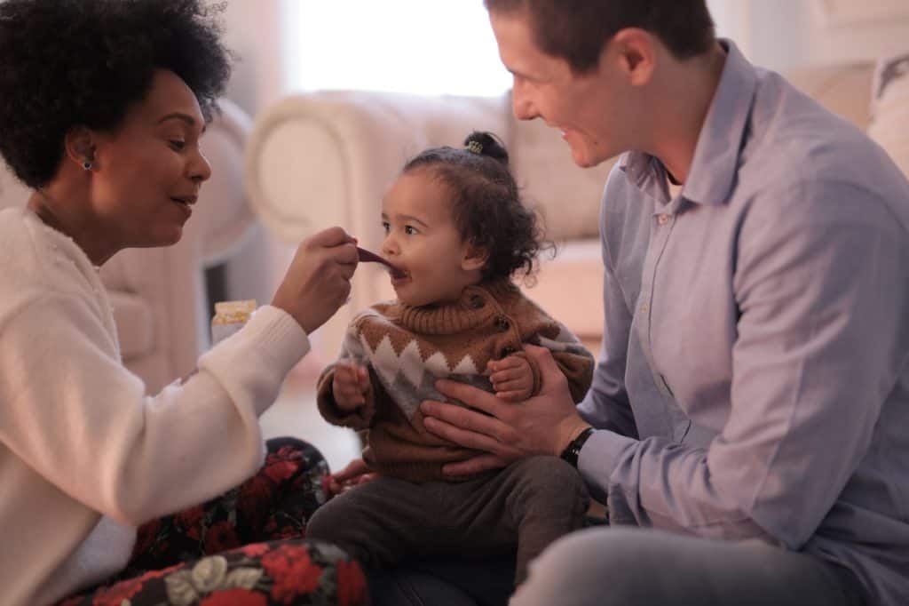 mom feeding baby while dad is holding her upright