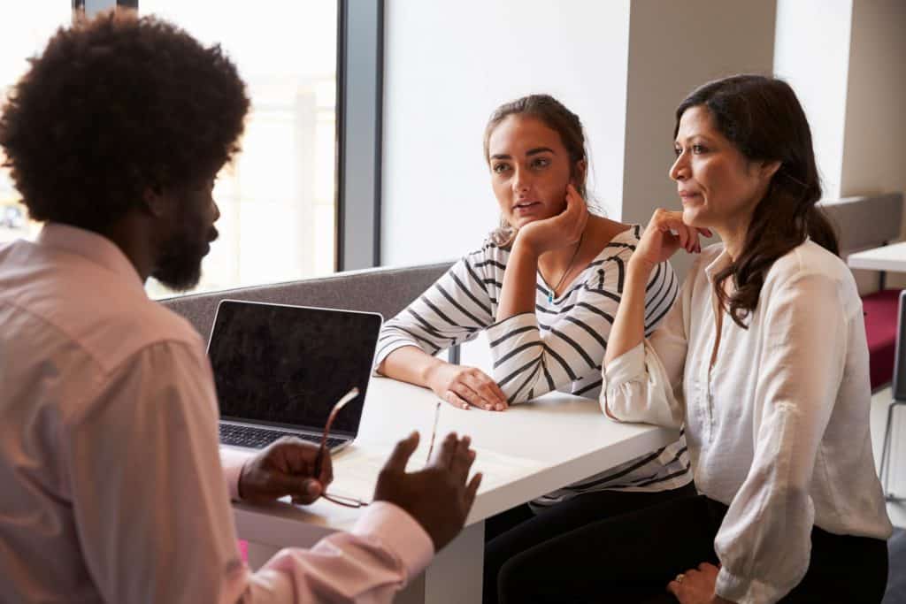 mother and daughter talking to a black man