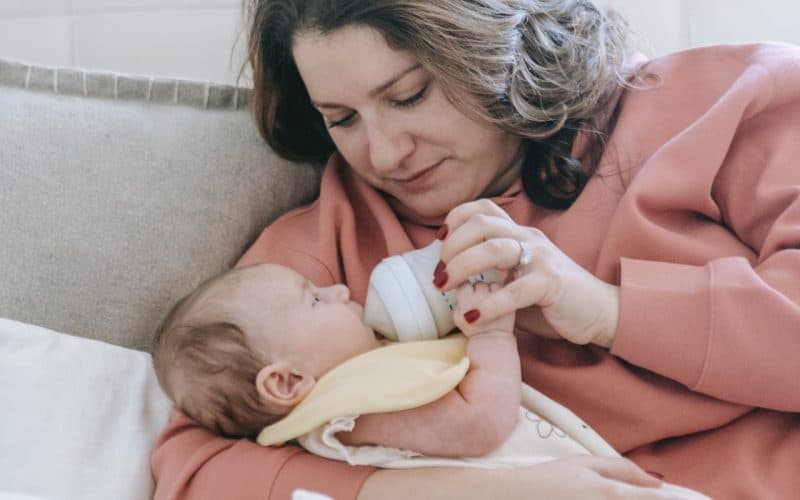 mother feeding bottle of milk to baby