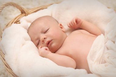 sleeping baby on a basket filled with white cotton