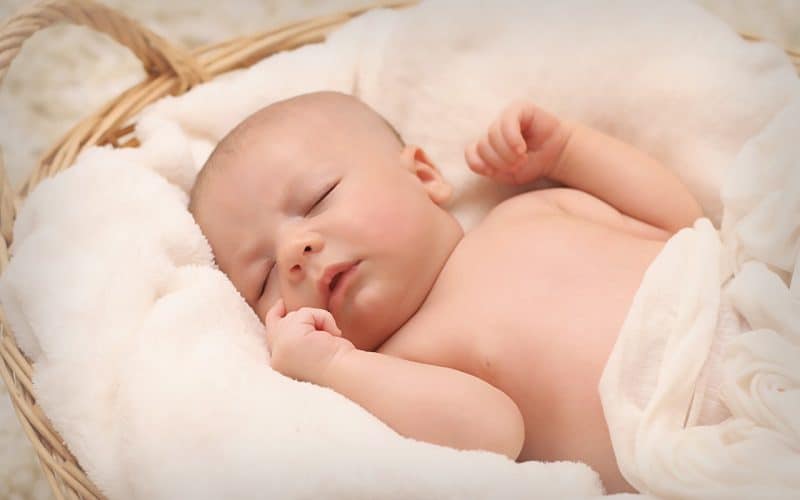 sleeping baby on a basket filled with white cotton