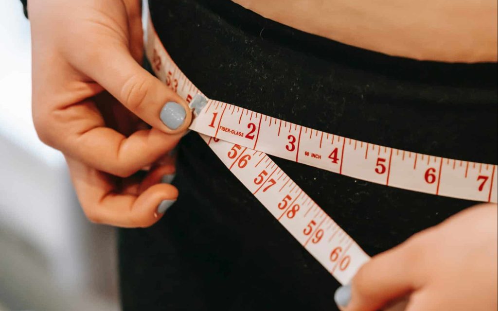 woman measuring her waist