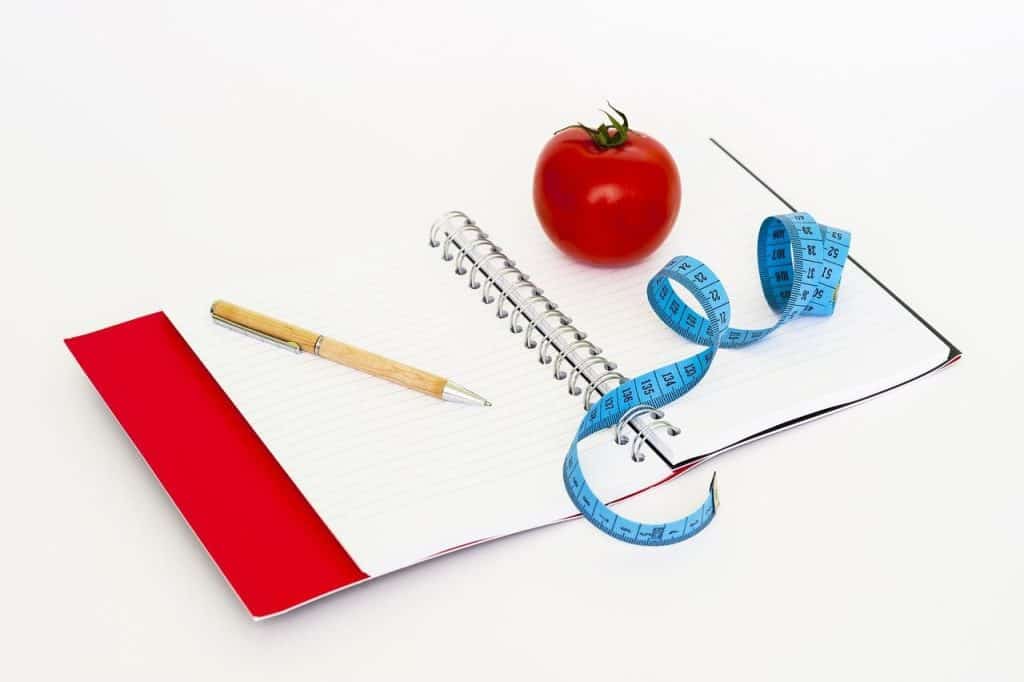 blank notebook, tomato and measuring tape