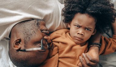 father and frowning kid on bed