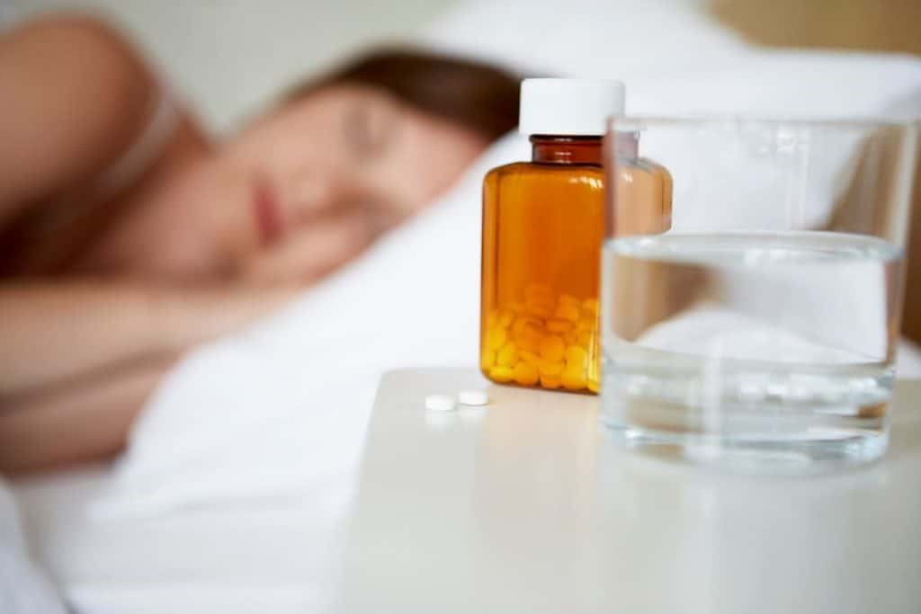 medications on table and sleeping woman