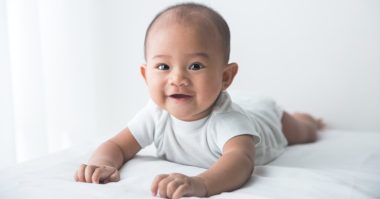 smiling baby tummy time on bed