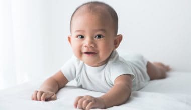 smiling baby tummy time on bed