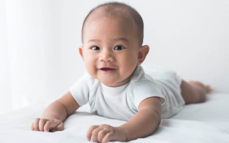 smiling baby tummy time on bed