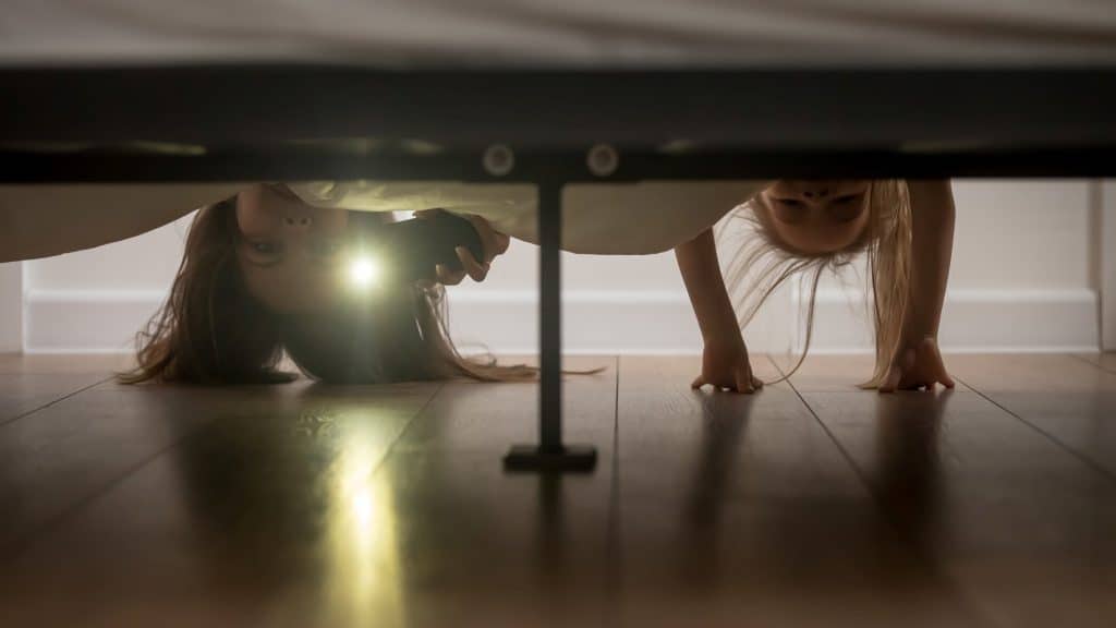 two girls looking under bed