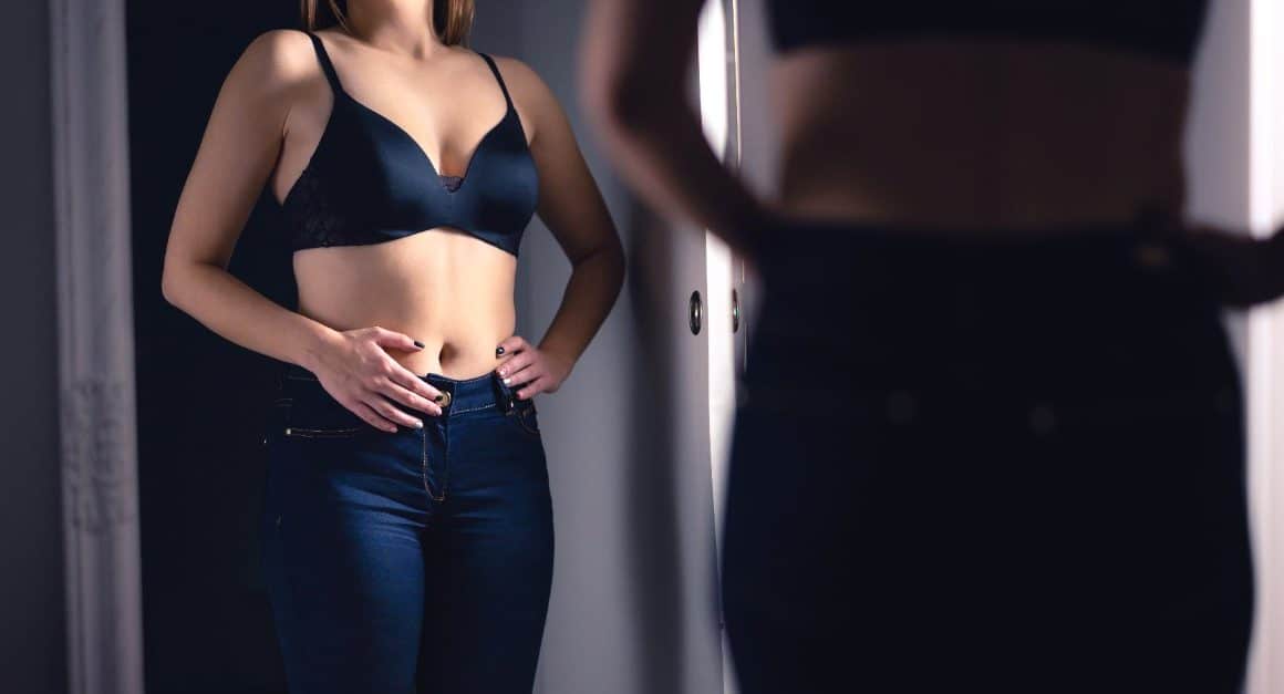 woman looking at her belly in the mirror