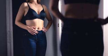 woman looking at her belly in the mirror