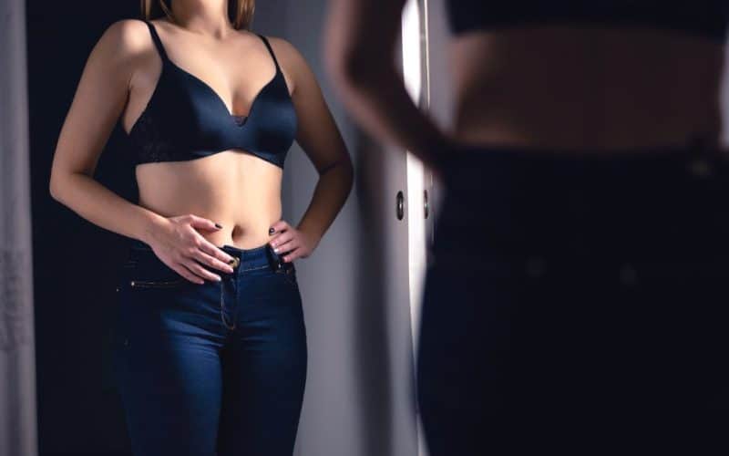 woman looking at her belly in the mirror