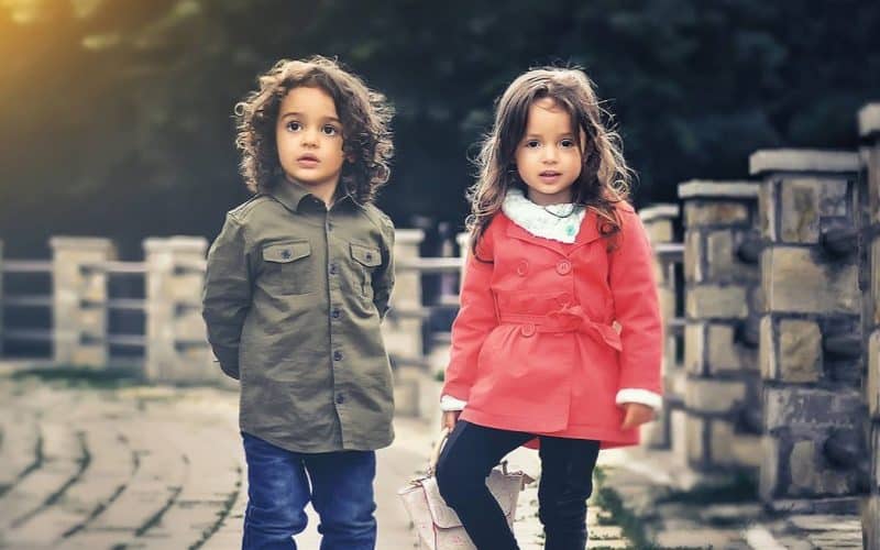 boy and girl standing near a concrete fence