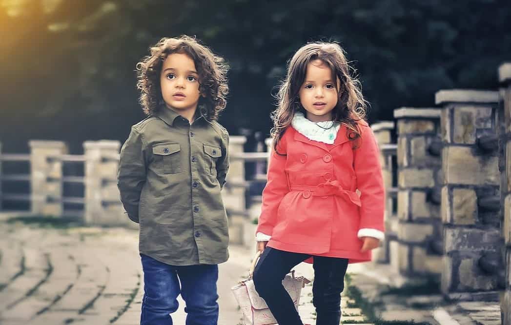 boy and girl standing near a concrete fence