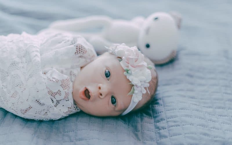 cute baby swaddled by embroidered cloth