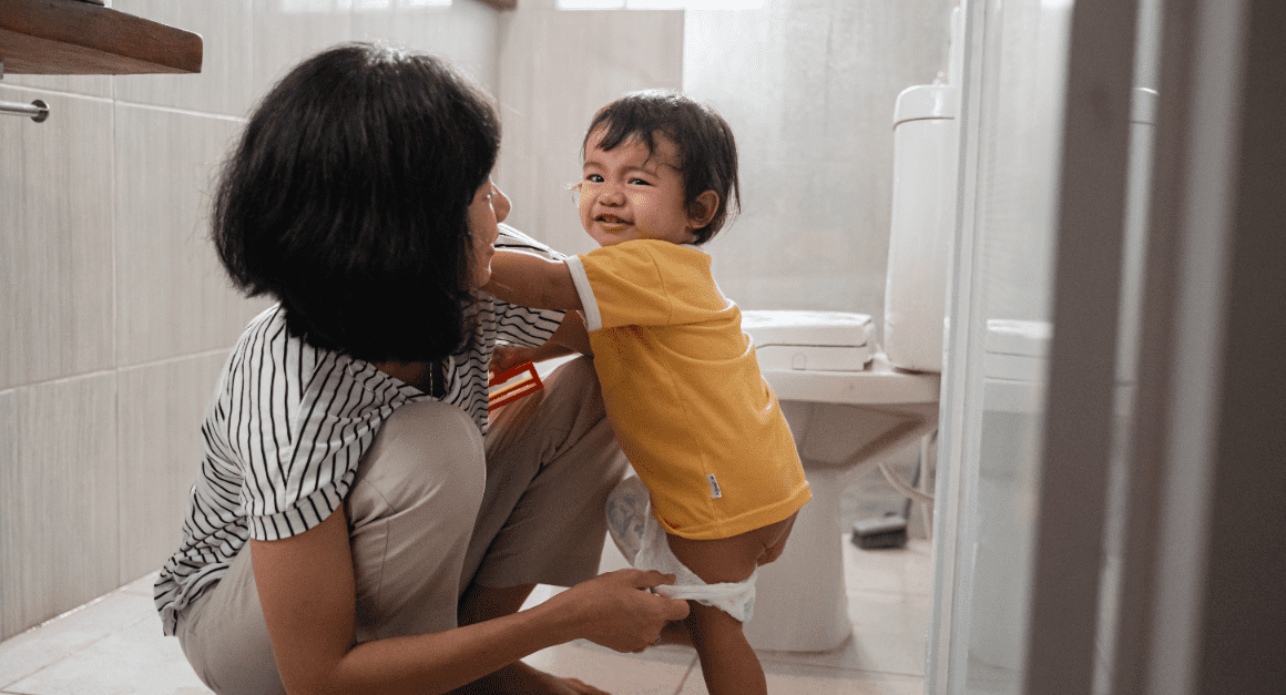mom assisting toddler in the bathroom