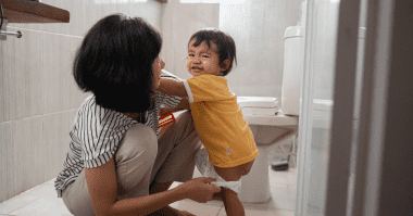 mom assisting toddler in the bathroom