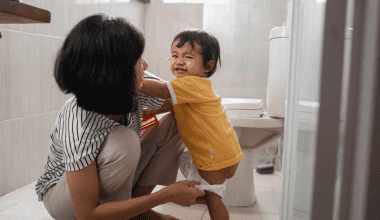 mom assisting toddler in the bathroom