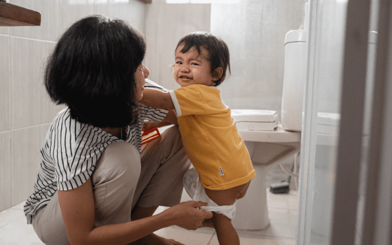 mom assisting toddler in the bathroom