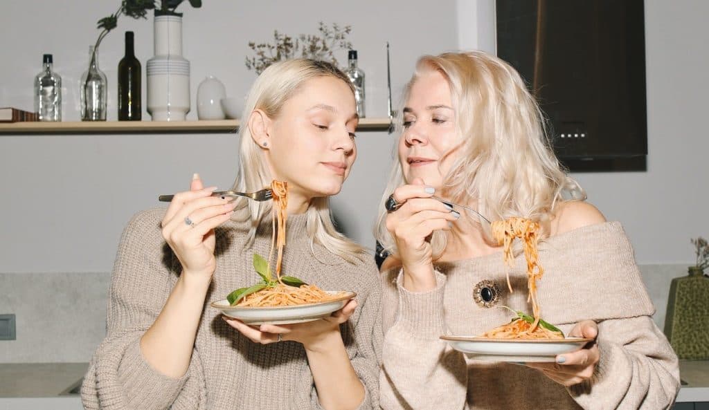 mother and daughter eating pasta