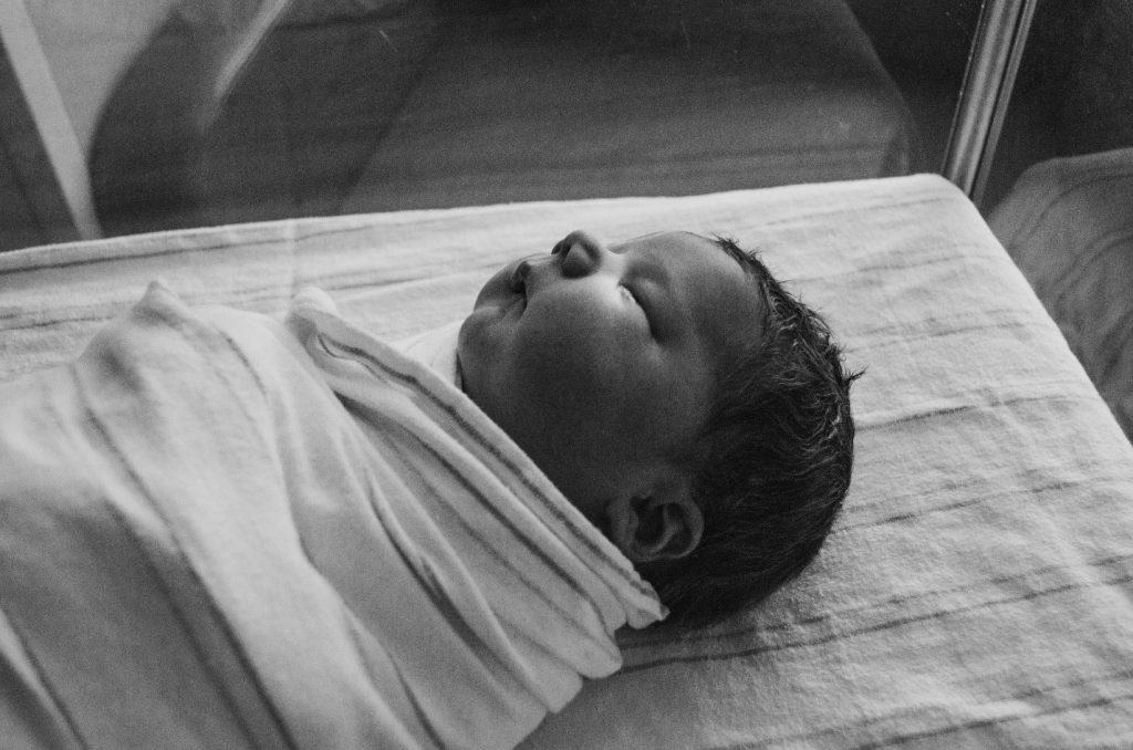 newborn swaddled by white cloth