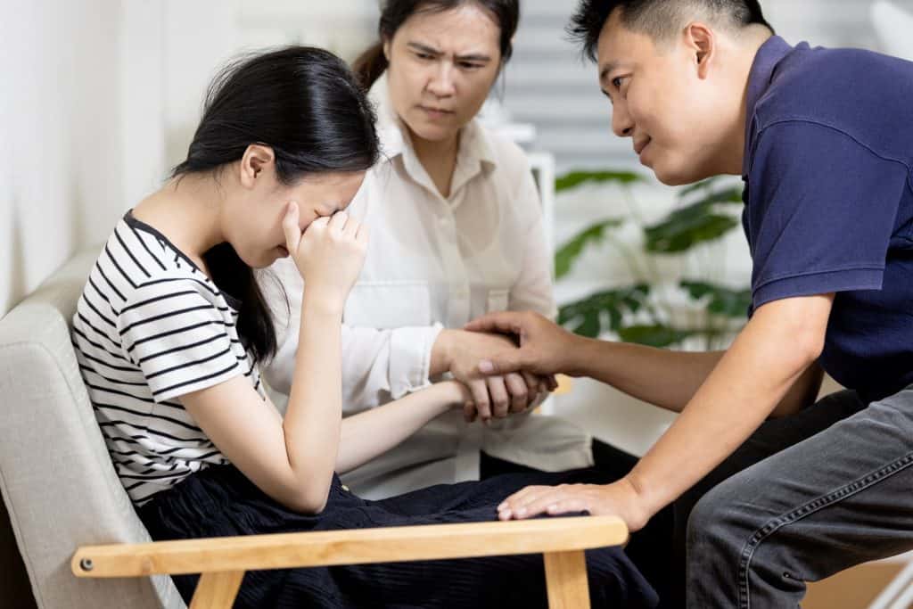 teenage girl crying in front of her parents