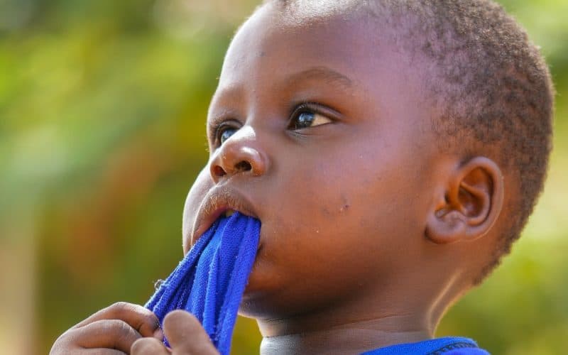child chewing on his shirt