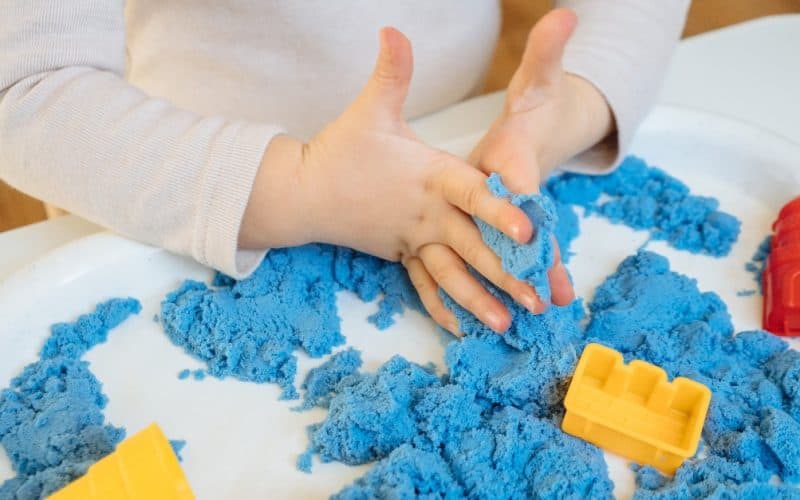 child playing with blue kinetic sand