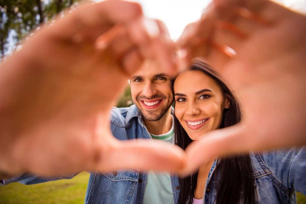 couple forming heart shape with their hands