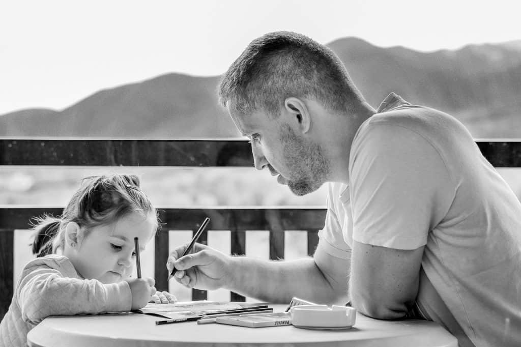 dad writing with little girl