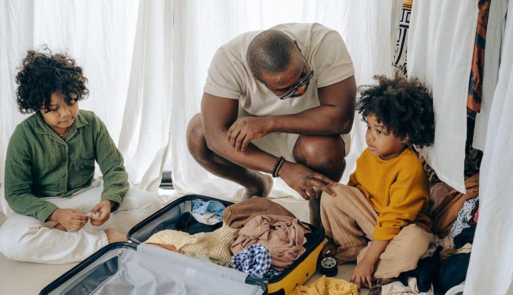 father sitting with his children near a suitcase