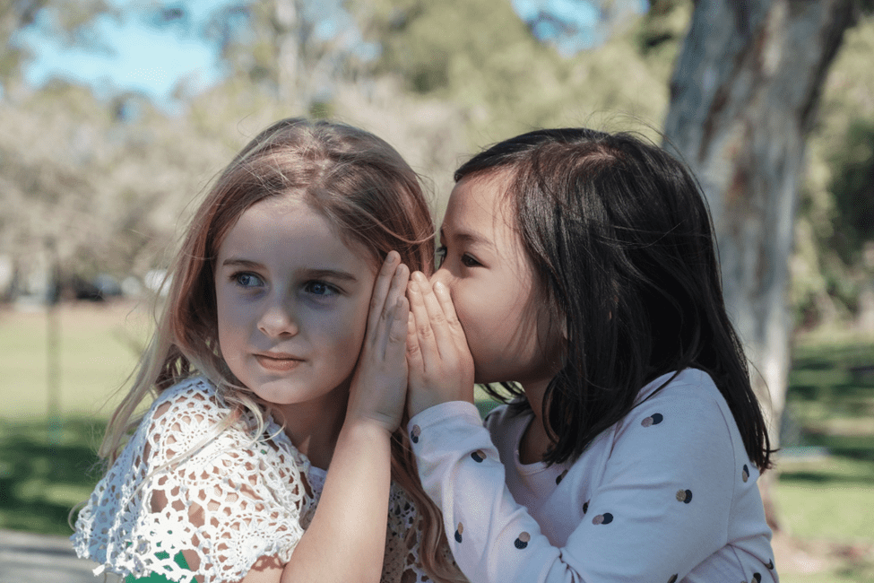 girl whispering something to her friend
