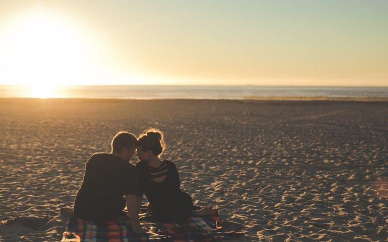 man and woman sitting on the beach