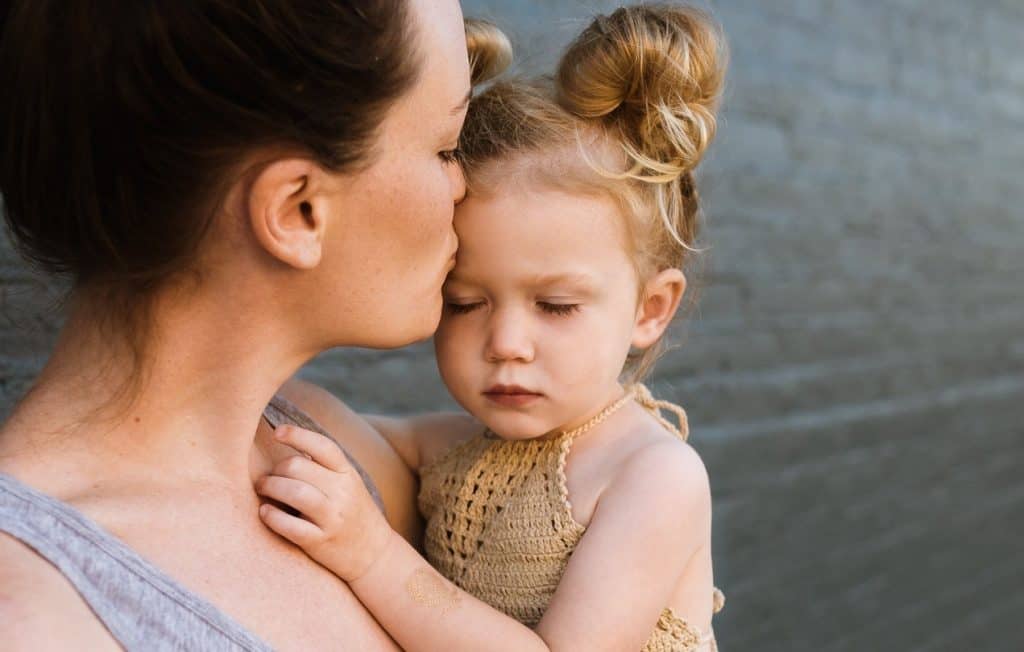 mom kissing baby girl's forehead