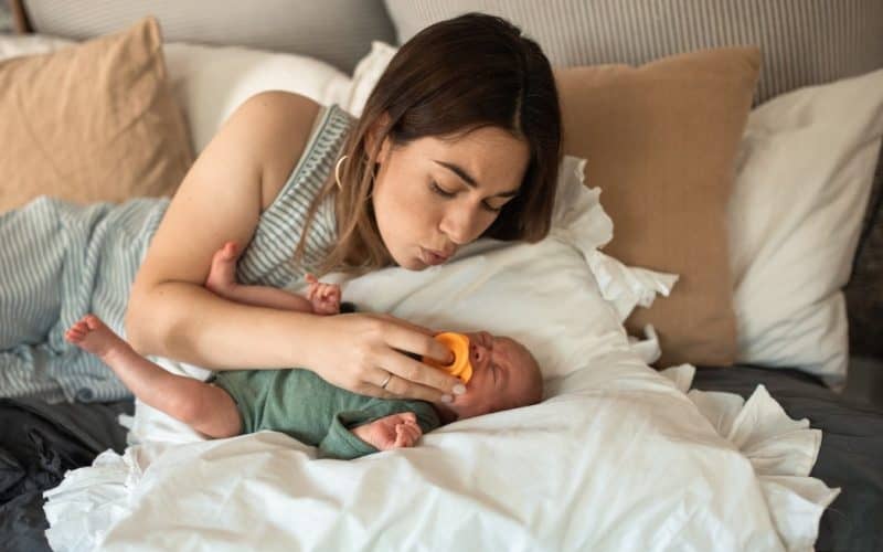 mom putting pacifier on baby