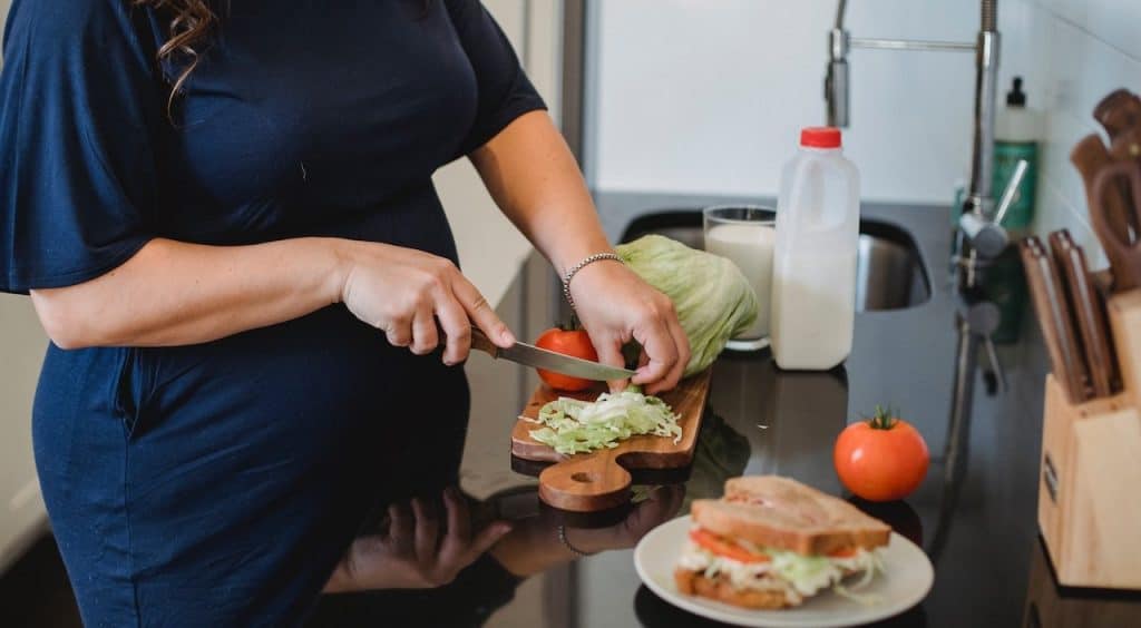 pregnant woman chopping lettuce leaves