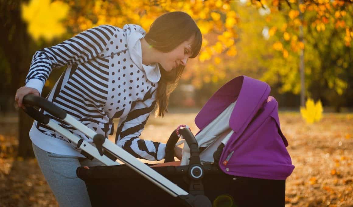 woman smiling at her baby on a stroller