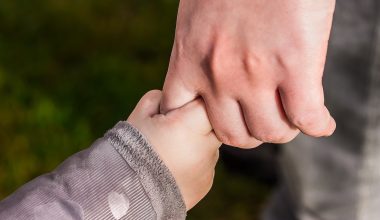 baby clutching a person's hands