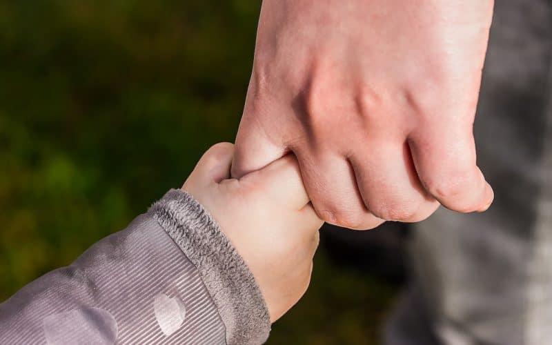 baby clutching a person's hands
