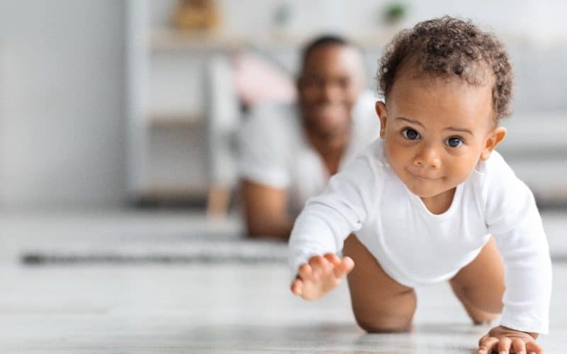 cute baby crawling in front of dad