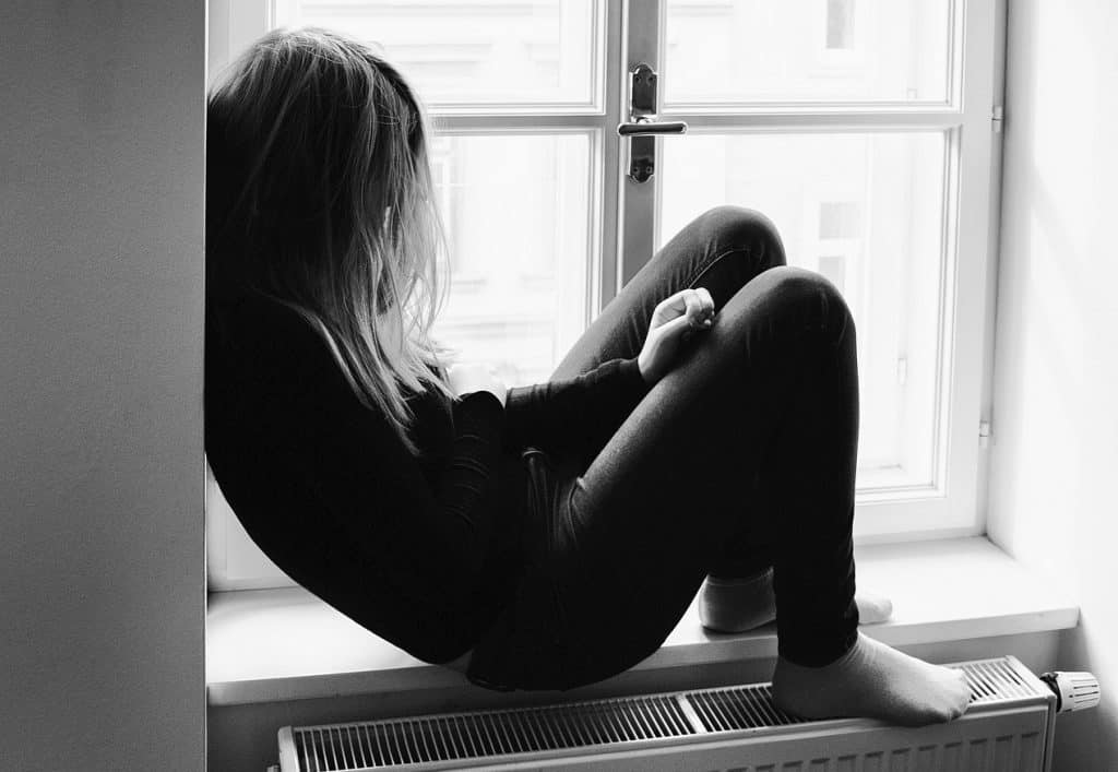 depressed teenager sitting in her window