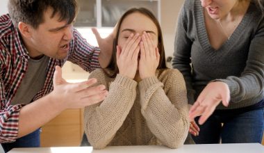 girl covering her face while parents scold her