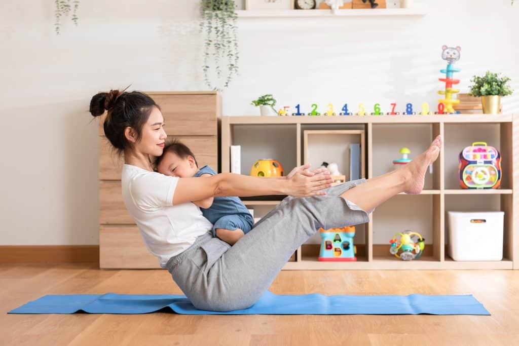 mom doing yoga while carrying baby