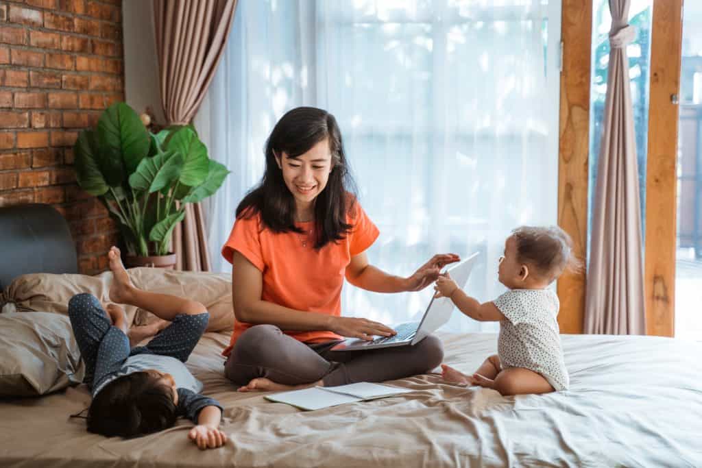 mom working while kids are on her bed