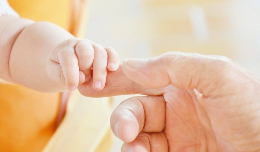 person touching baby's hands