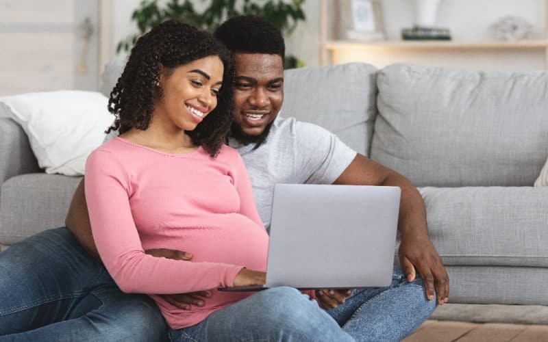 pregnant couple watching something from laptop